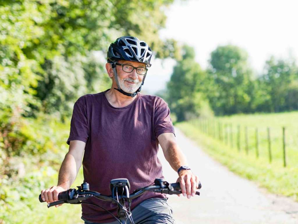 Älterer Mann macht Radtour mit E-Bike und trägt Notrufarmband für den mobilen Notruf